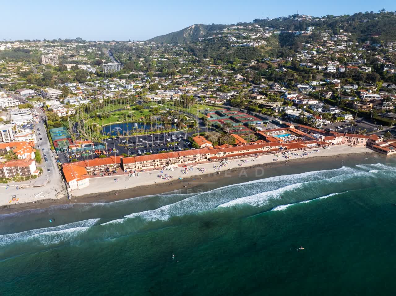Aerial view of the beach, the surf and palm trees at La Jolla Shores, with people walking.