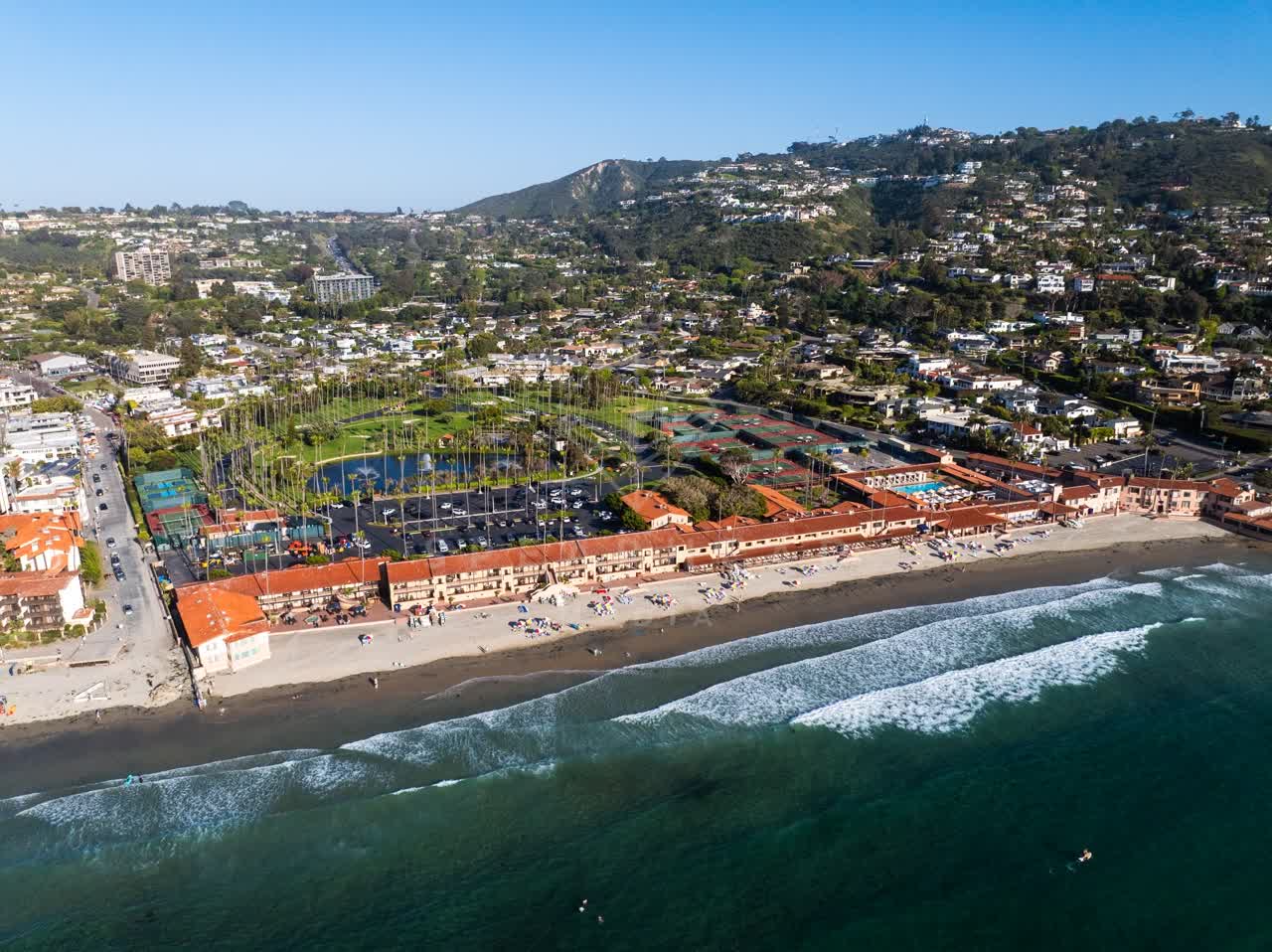 Aerial view of the beach, the surf and palm trees at La Jolla Shores, with people walking.