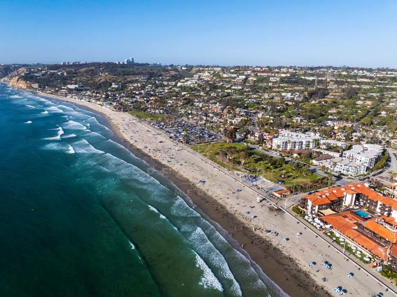 Aerial view of the beach, the surf and palm trees at La Jolla Shores, with people walking.