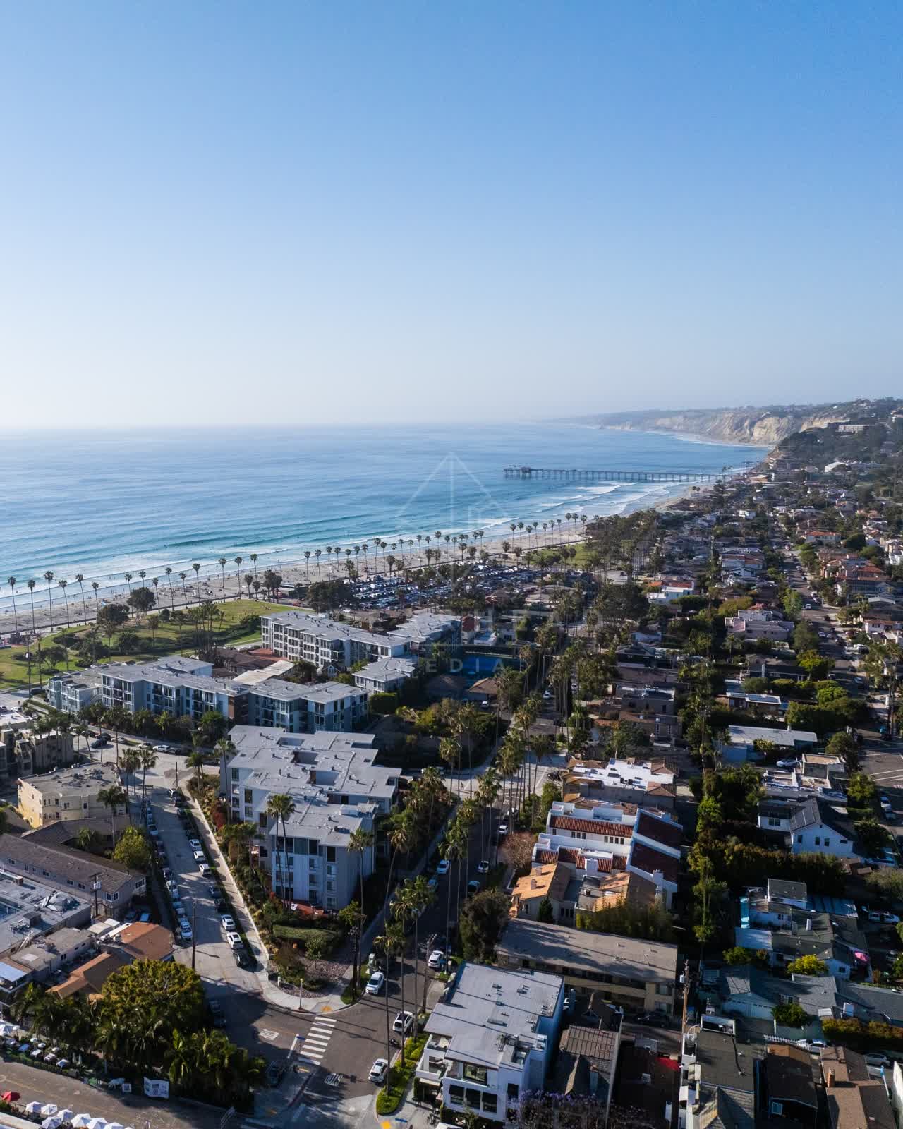 Aerial view of a residential street, the pier and palm trees at La Jolla Shores.