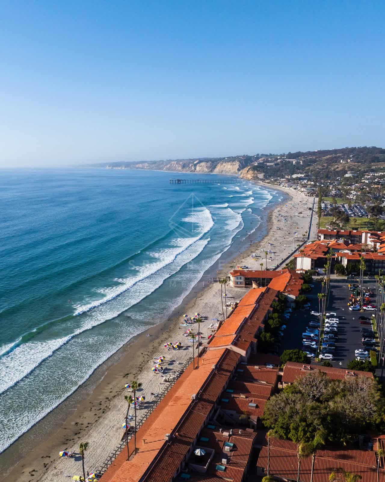 Aerial view of the beach, the surf and the pier at La Jolla Shores, with people walking.