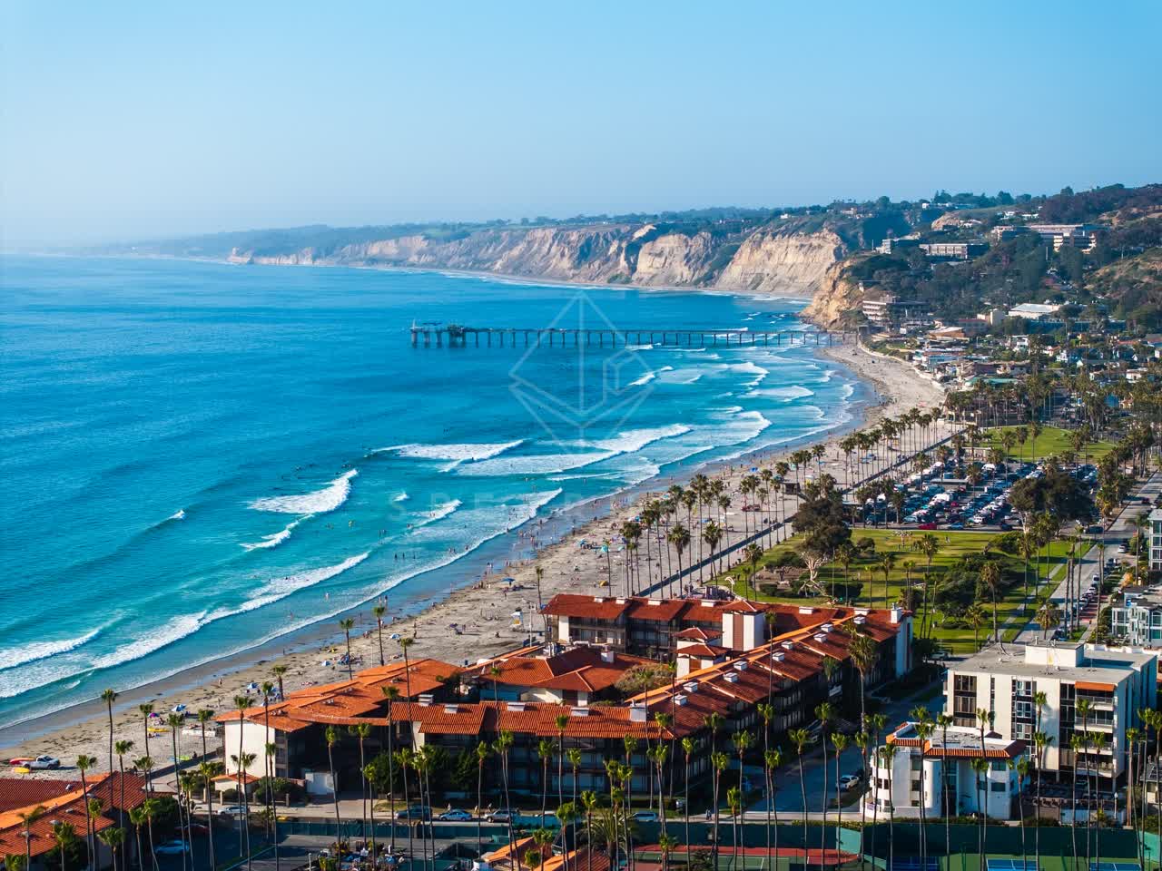 Aerial view of the beach, the surf and the pier at La Jolla Shores, with people walking.