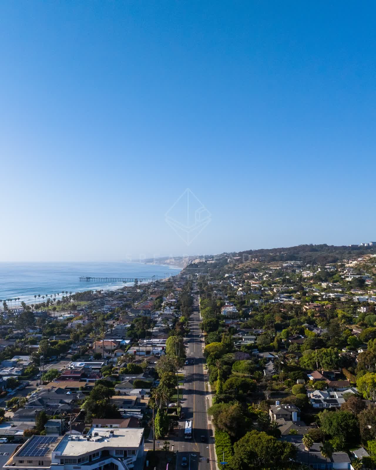 Aerial view of a residential street, the pier and palm trees at La Jolla Shores.