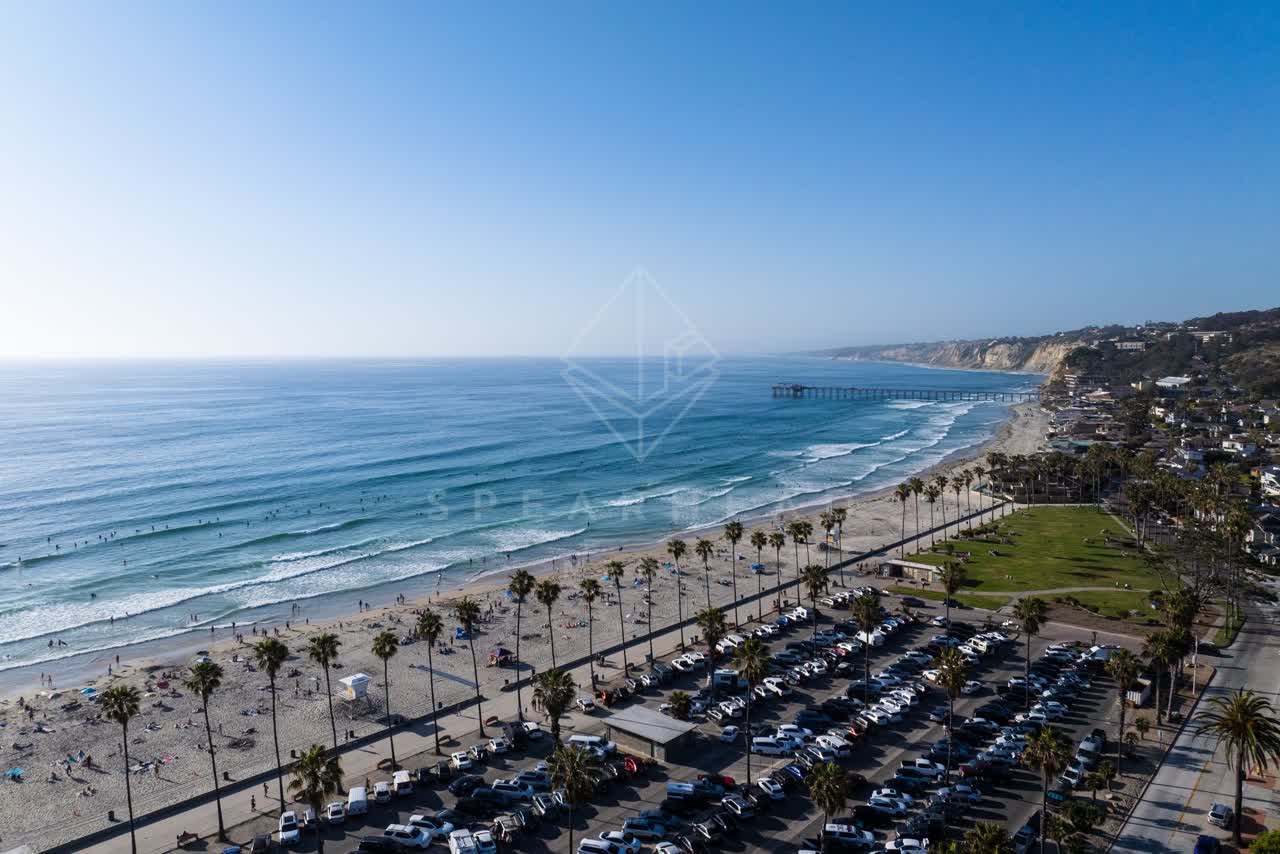 Aerial view of the beach, the surf and the pier at La Jolla Shores, with people walking.