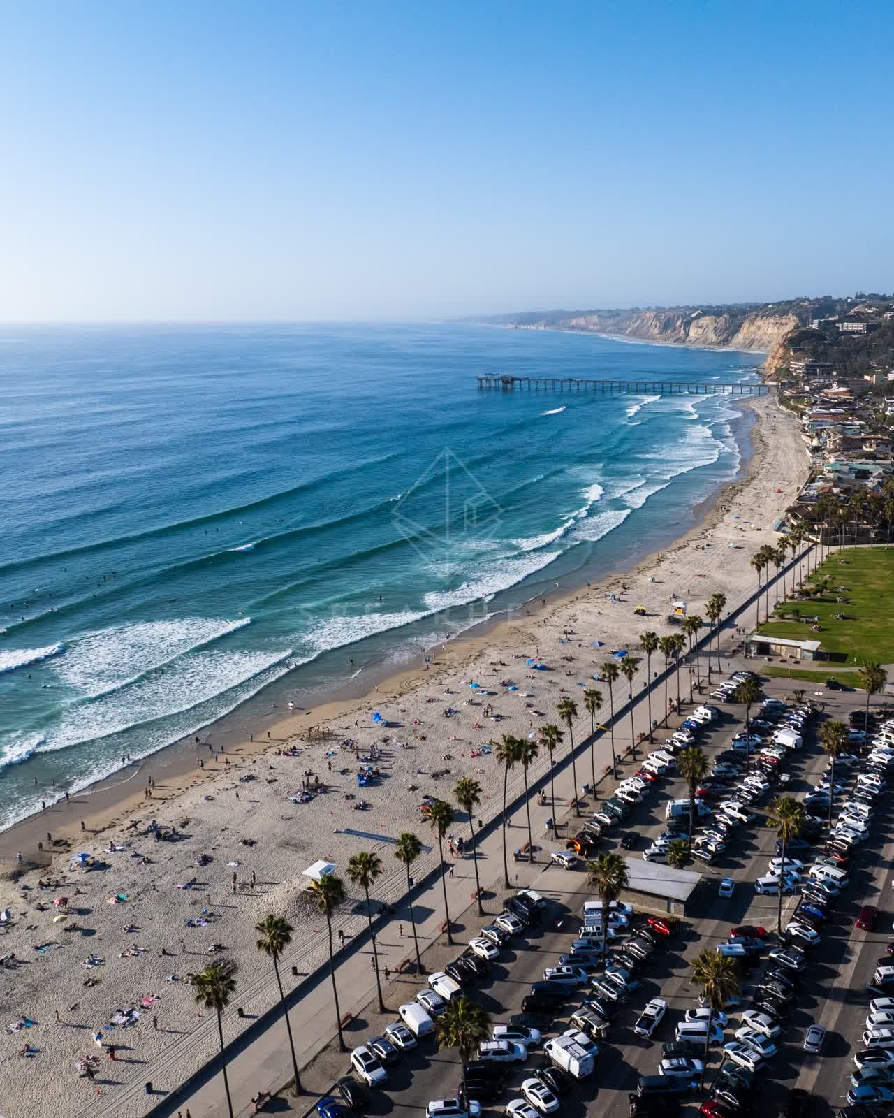 Aerial view of the beach, the surf and the pier at La Jolla Shores, with people walking.