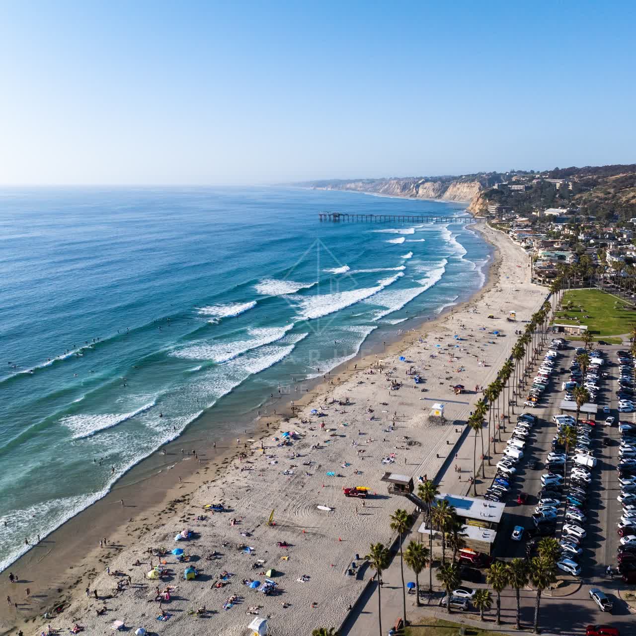 Aerial view of the beach, the surf and the pier at La Jolla Shores, with swimmers in the water.