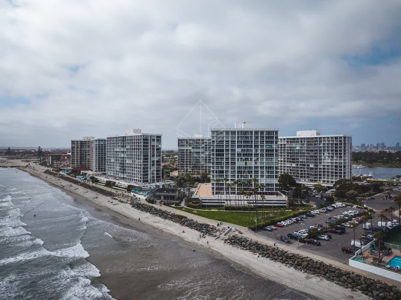 Aerial view of the beach, palm trees and the ocean at Coronado Beach, with people walking.