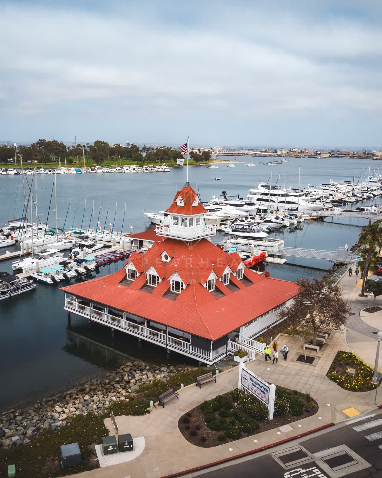 Aerial view of the harbor, boats and the bay at Coronado Beach, with people walking.