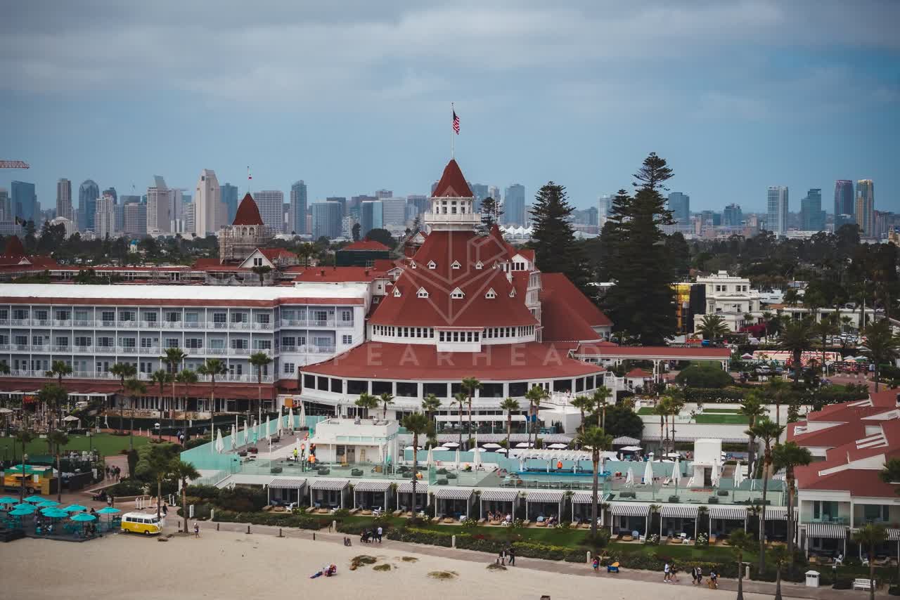 Aerial view of the beach, the skyline and palm trees at Coronado Beach, with people walking.