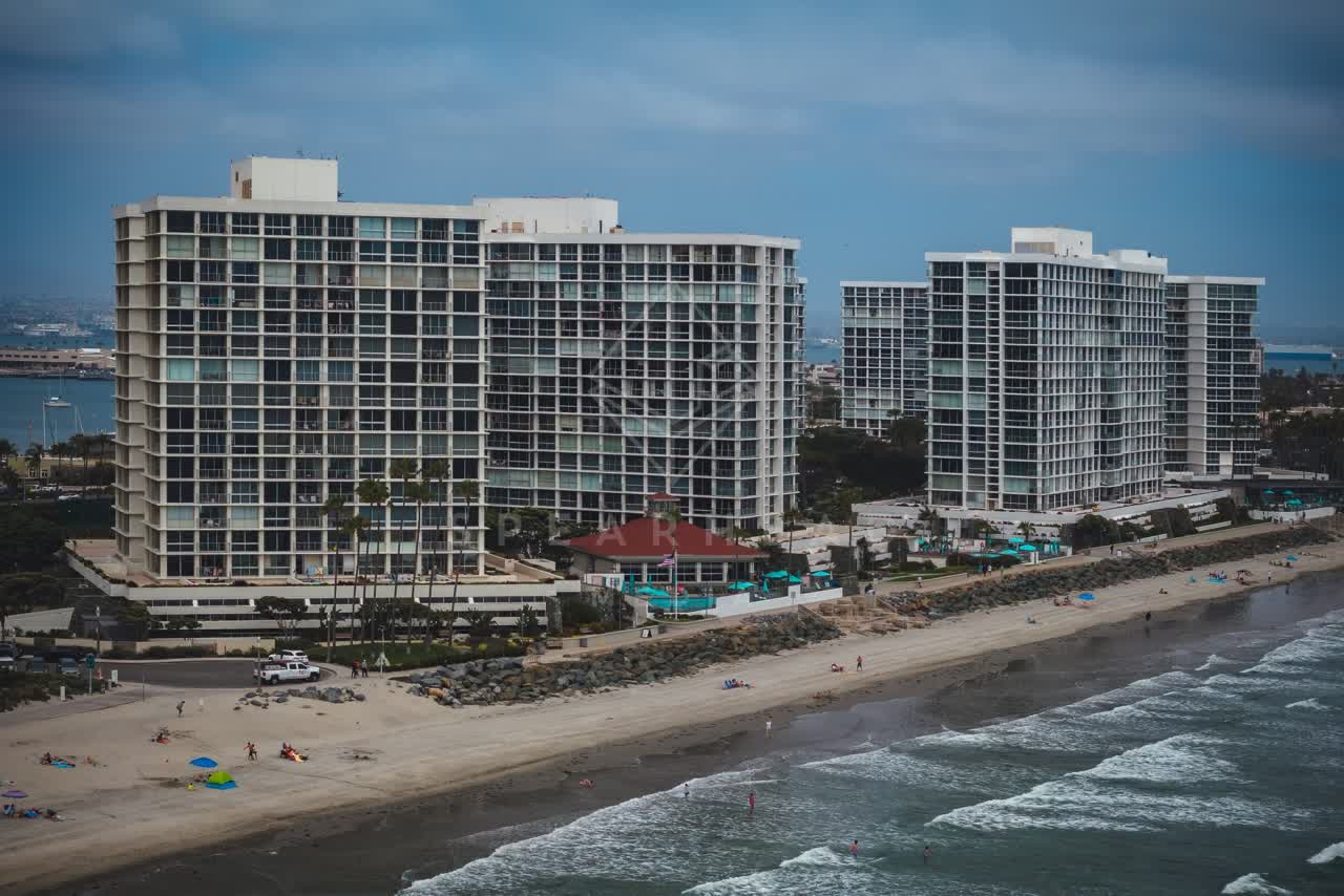 Aerial view of the beach, the surf and palm trees at Coronado Beach, with people walking.