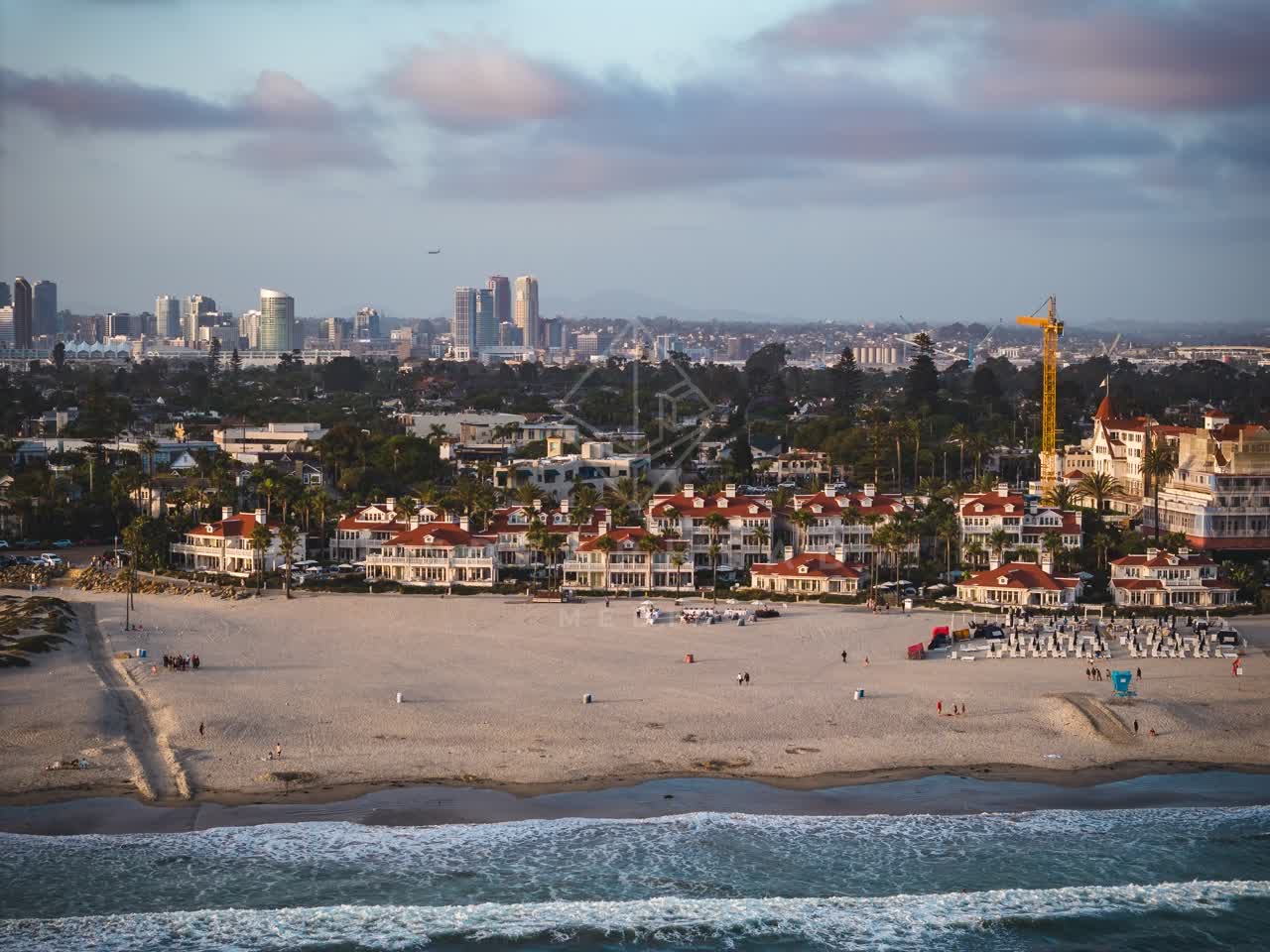 Aerial view of the beach, the surf and the skyline at Coronado Beach, with people walking.