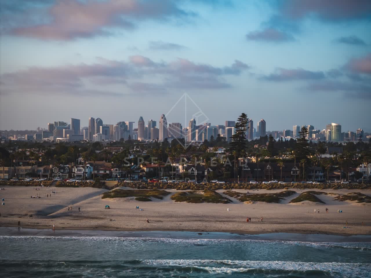 Aerial view of the beach, the skyline and palm trees at Coronado Beach, with people walking.