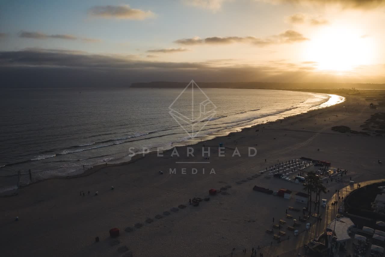 Aerial view of the beach, the surf and palm trees at Coronado Beach, with people walking.