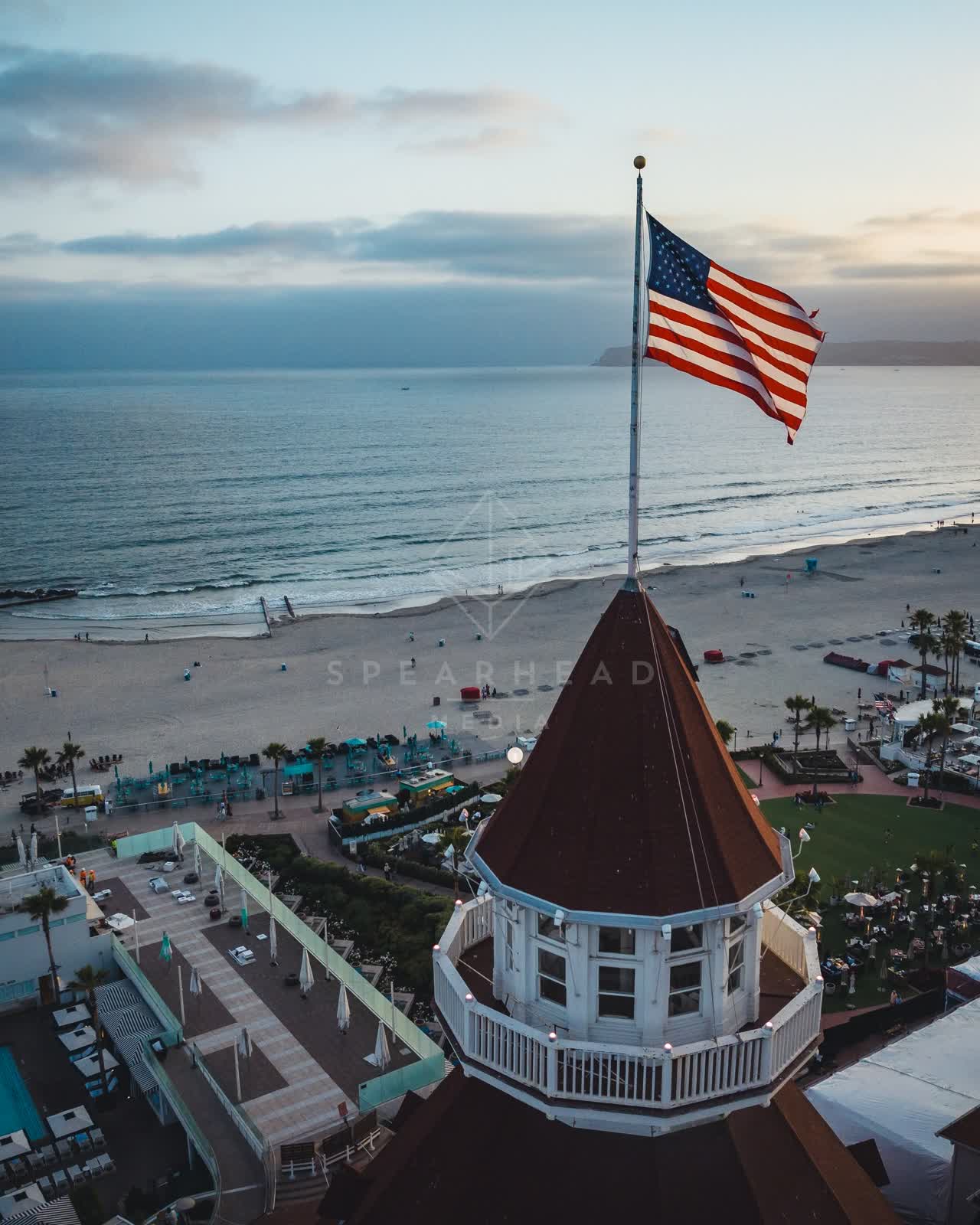 Low aerial view of the beach, palm trees and the ocean at Coronado Beach, with people walking.