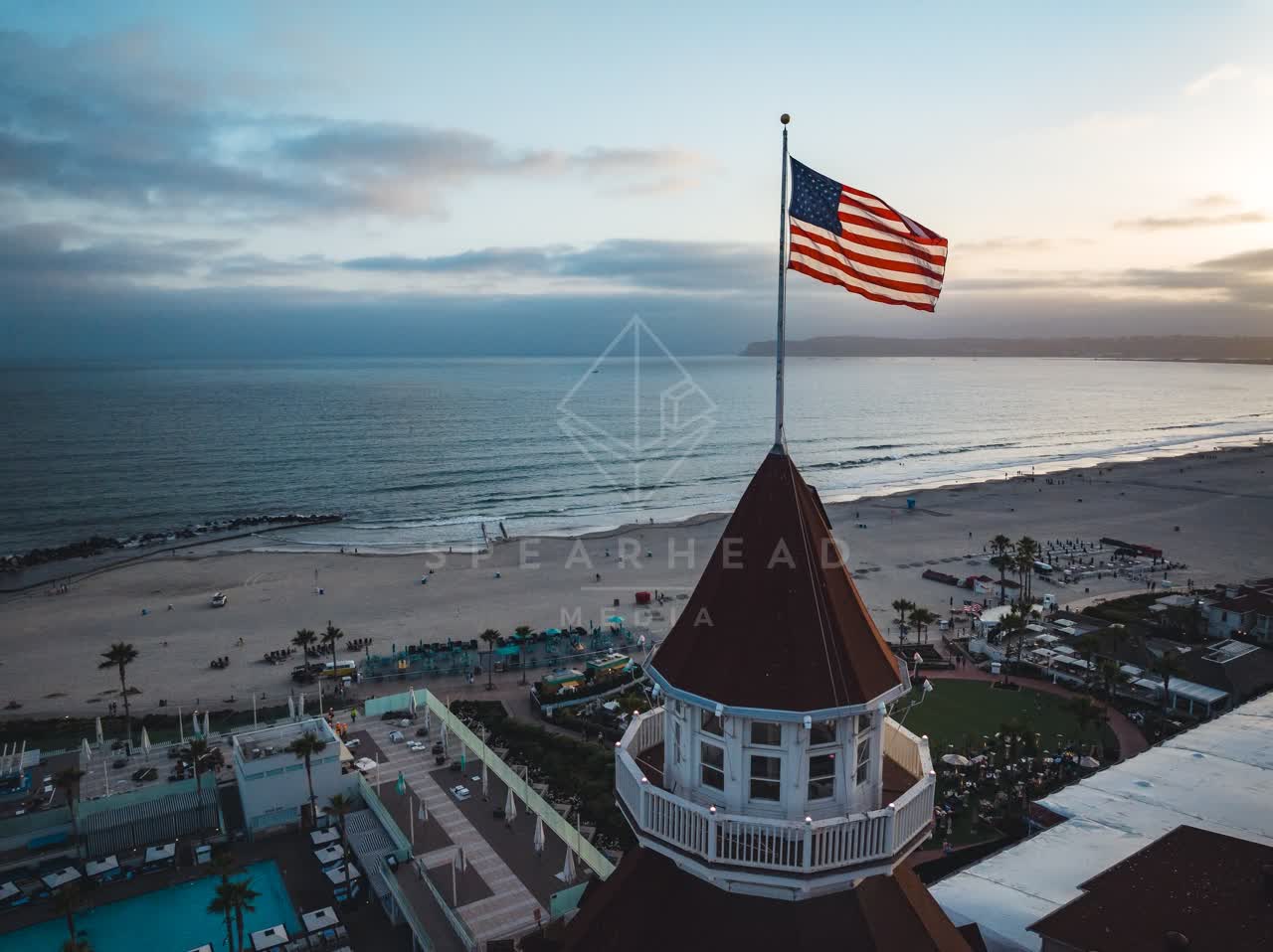 Low aerial view of the beach, palm trees and the ocean at Coronado Beach, with people walking.
