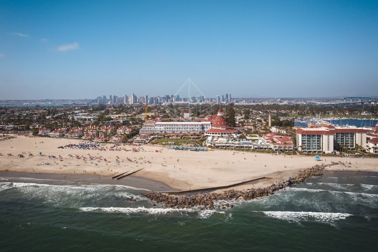 Aerial view of the beach, the bridge and the skyline at Coronado Beach, with people walking.