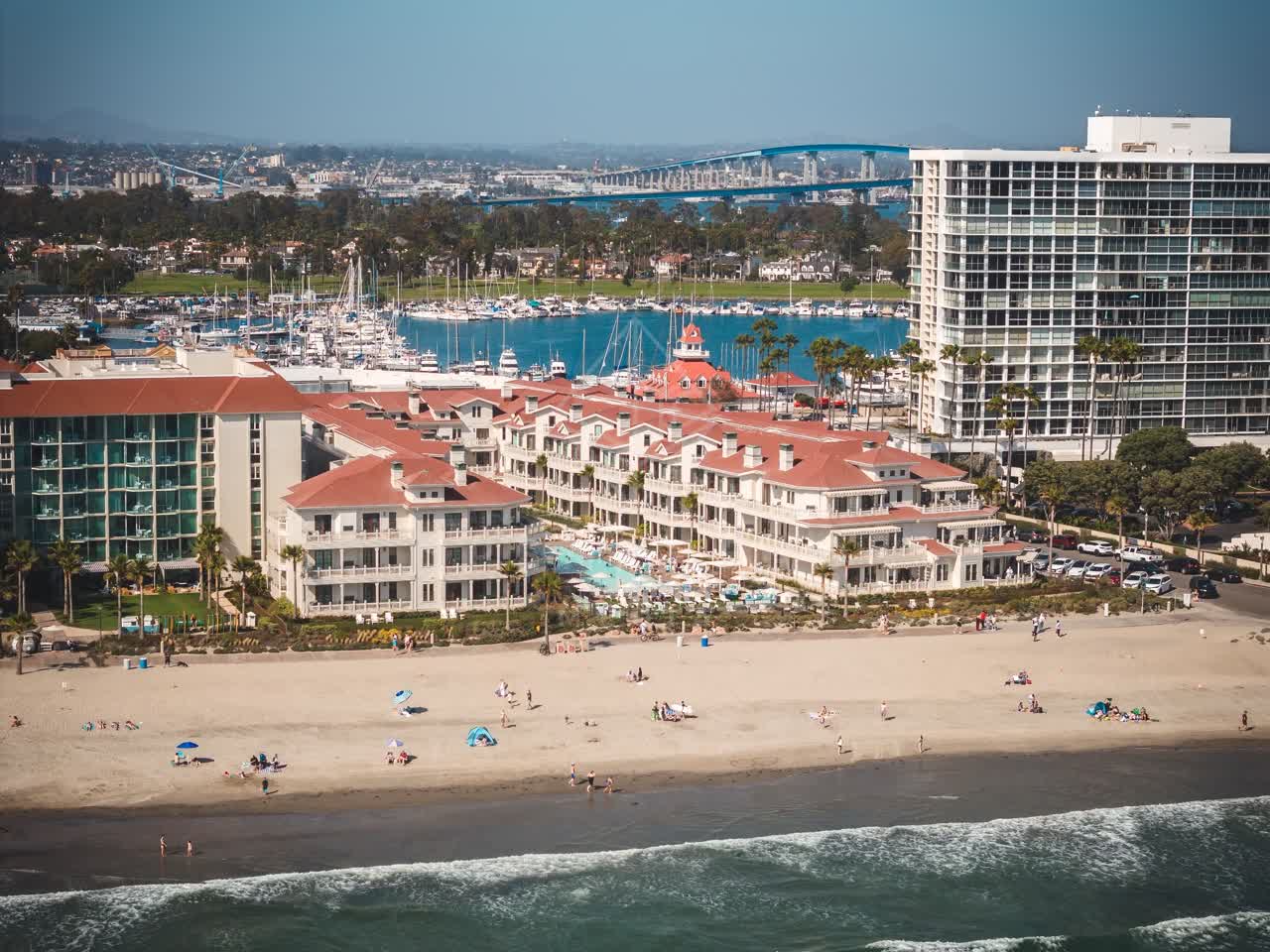 Aerial view of the beach, the bridge and boats at Coronado Beach, with people walking.