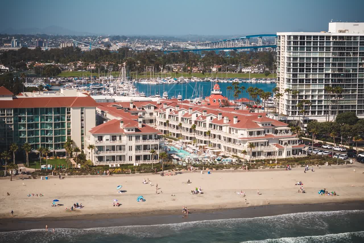 Aerial view of the beach, the bridge and boats at Coronado Beach, with people walking.