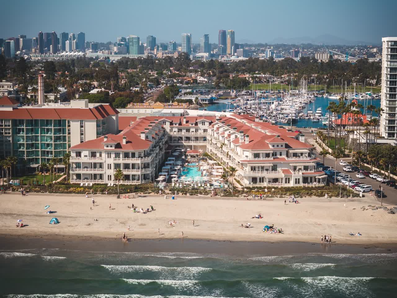 Aerial view of the beach, the skyline and boats at Coronado Beach, with people walking.