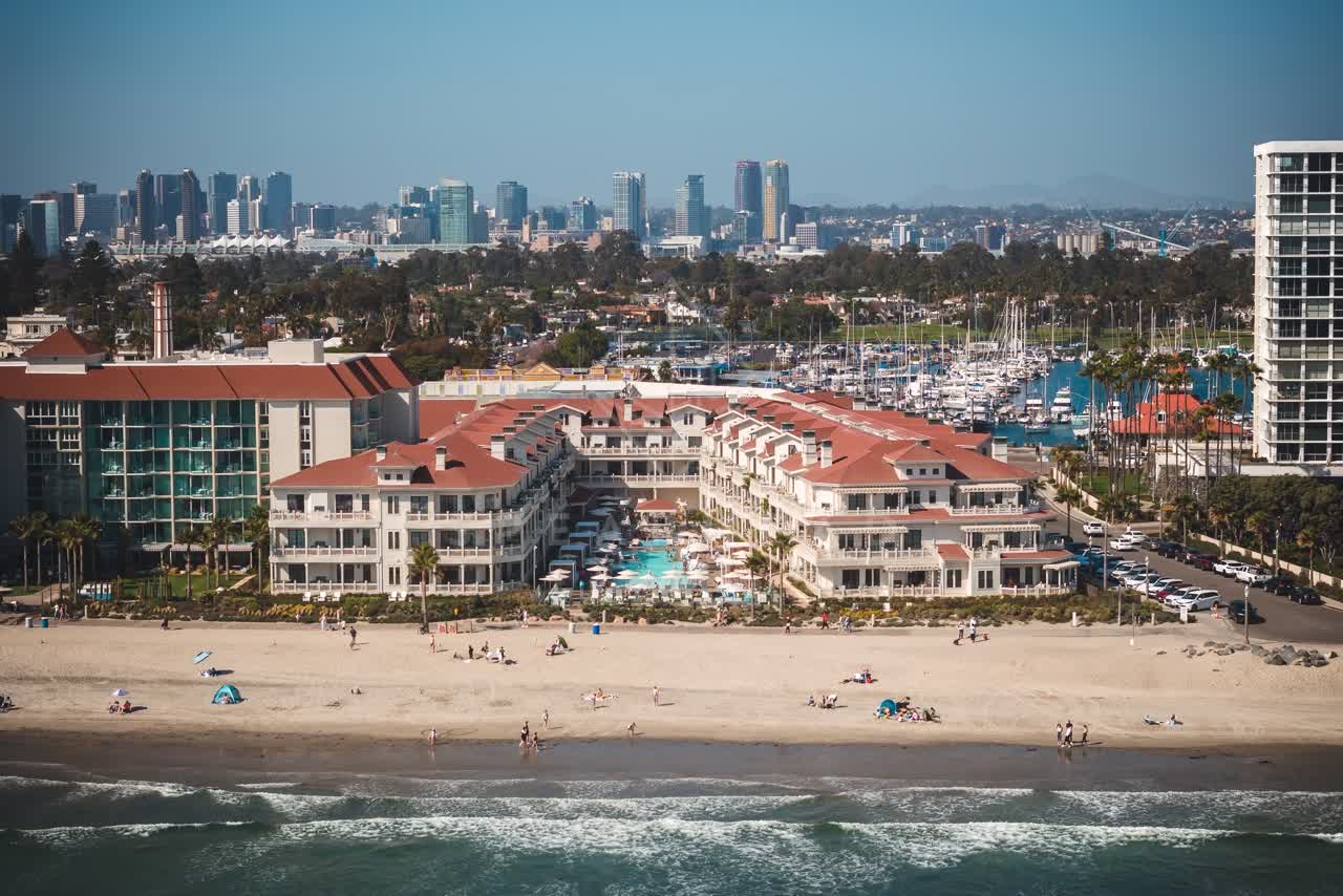 Aerial view of the beach, the skyline and boats at Coronado Beach, with people walking.