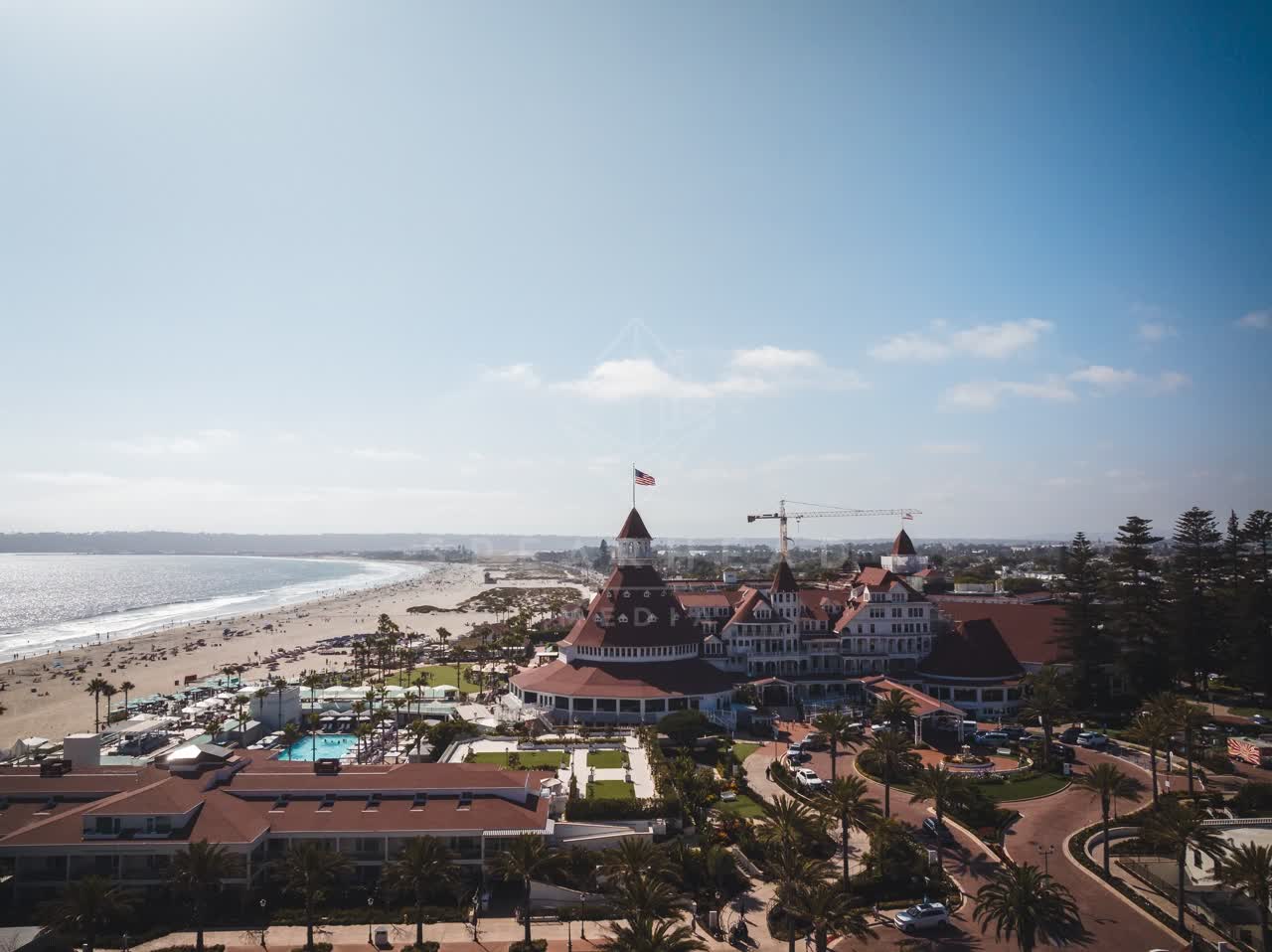 Aerial view of the beach, palm trees and the ocean at Coronado Beach, with people walking.