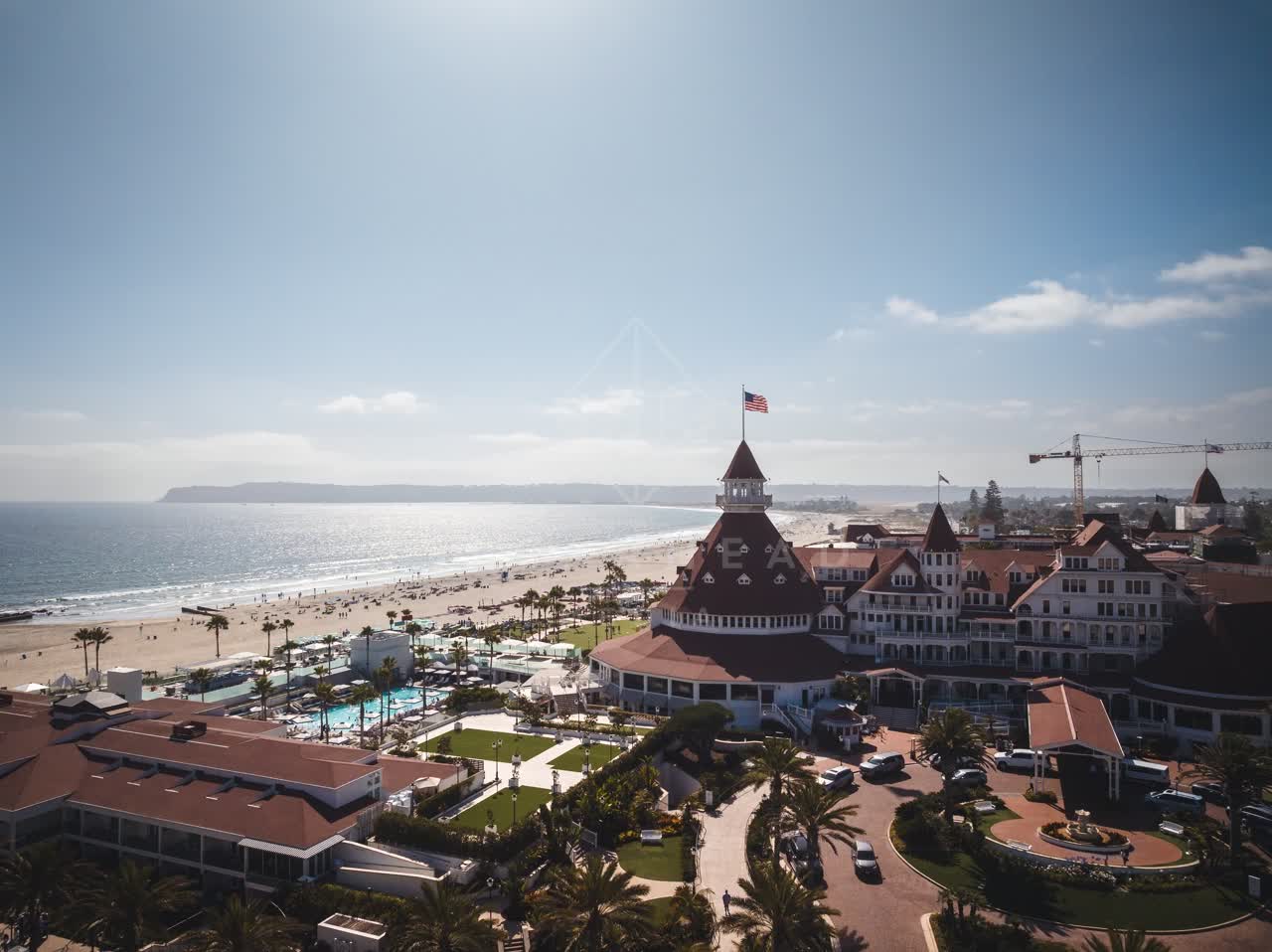 Aerial view of the beach, palm trees and the ocean at Coronado Beach, with people walking.