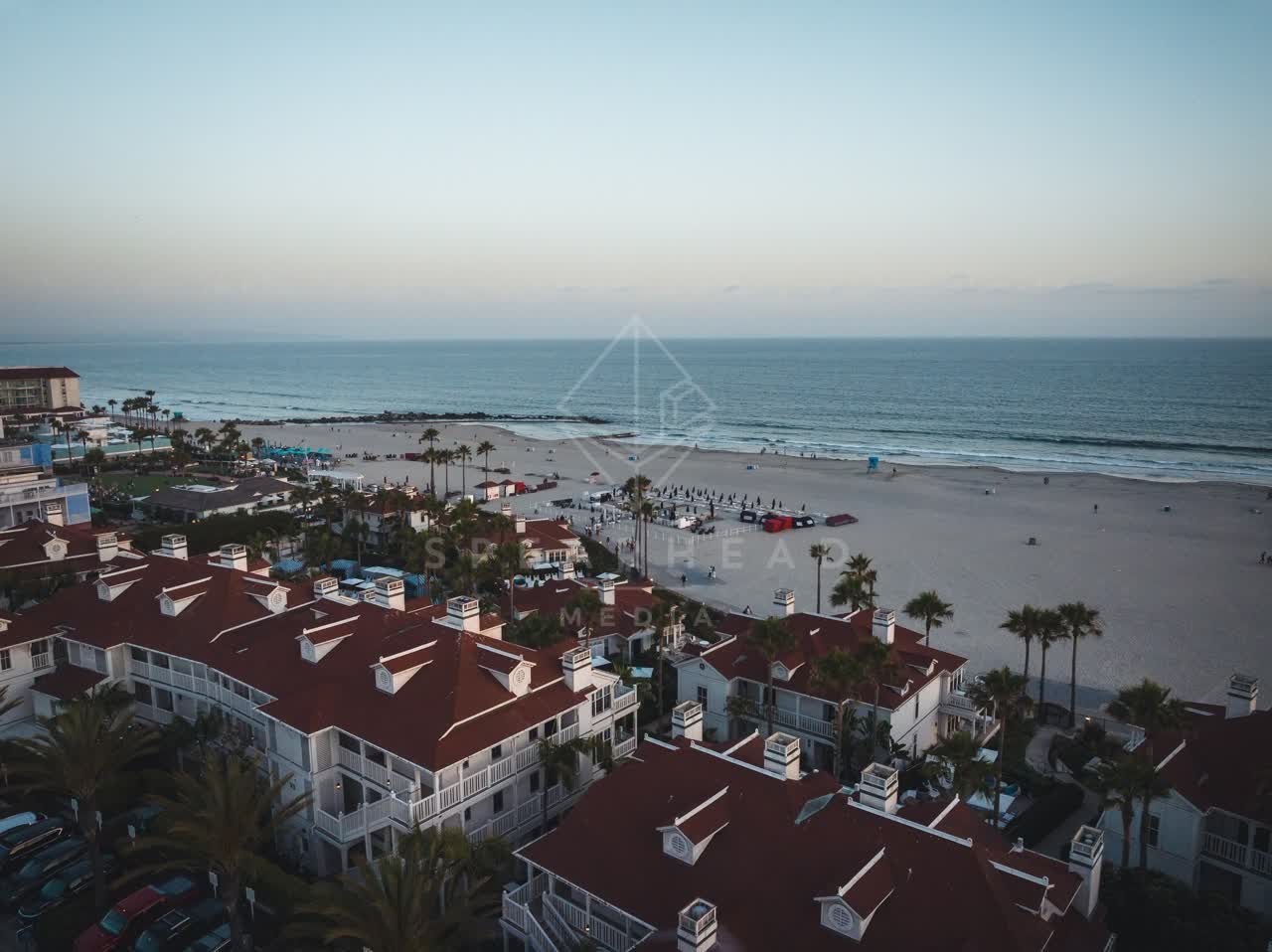 Aerial view of the beach, palm trees and the ocean at Coronado Beach, with people walking.