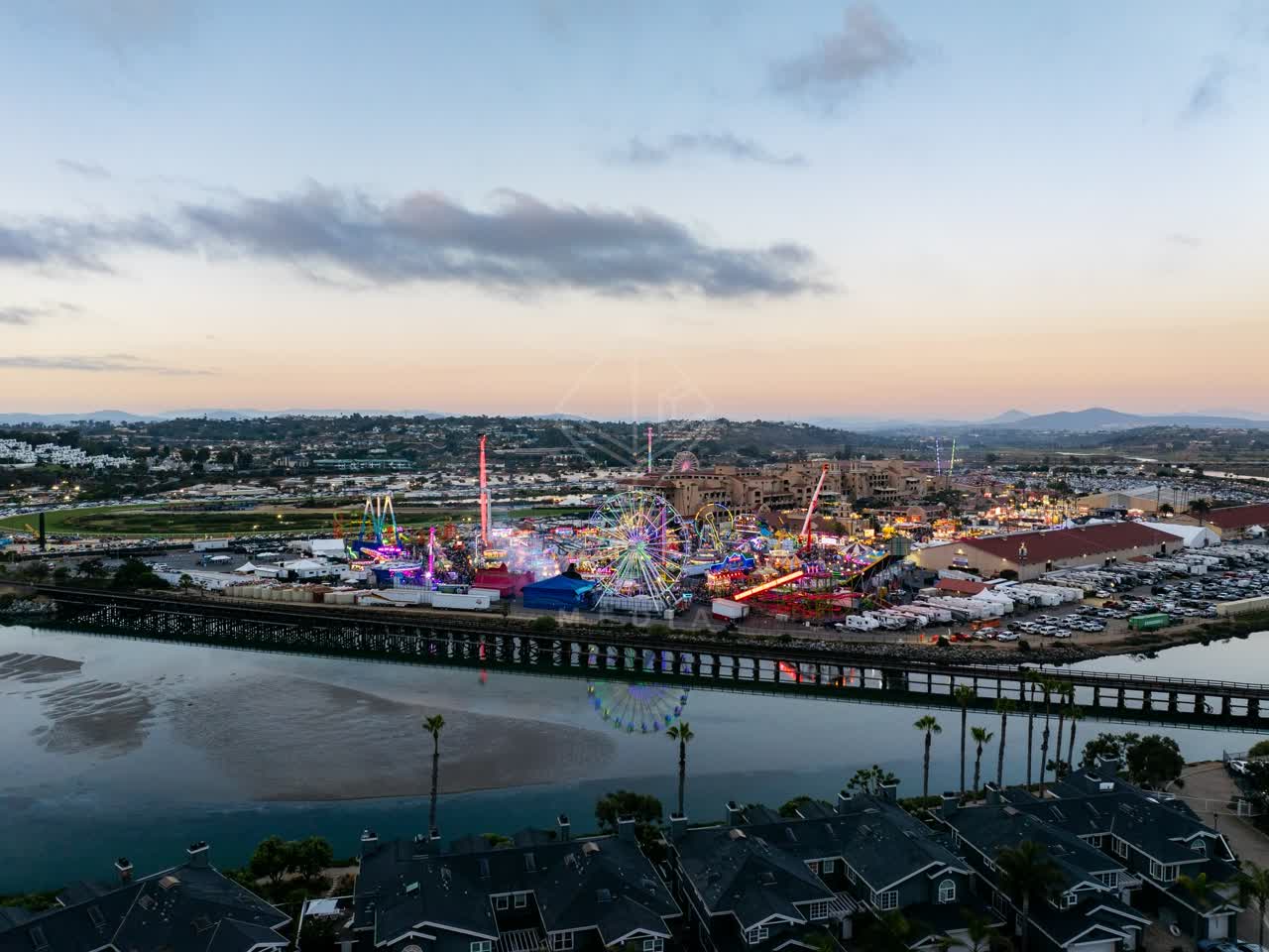 Aerial view of the country inland, homes and traffic in Del Mar, with a crowd gathered.