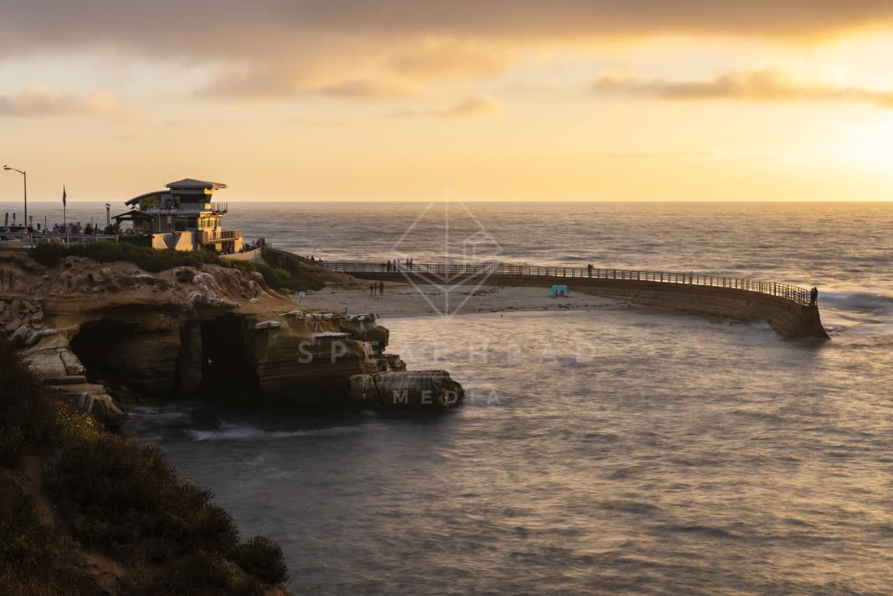 Elevated view of the cliffs, the ocean and the bay at La Jolla Cove, with people walking.