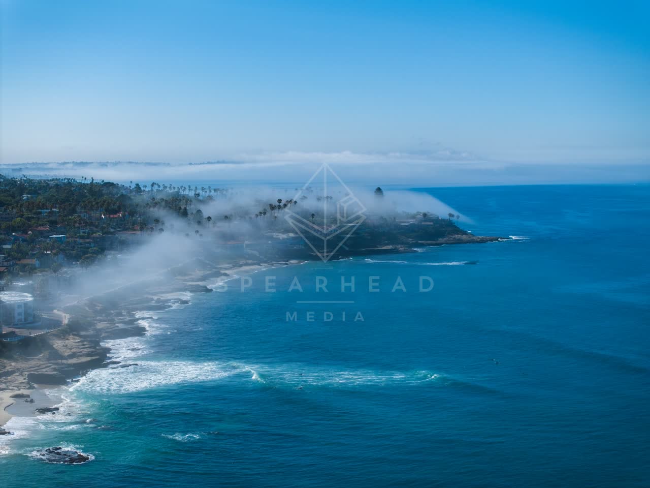 Aerial view of the cliffs, the surf and palm trees at Windansea.