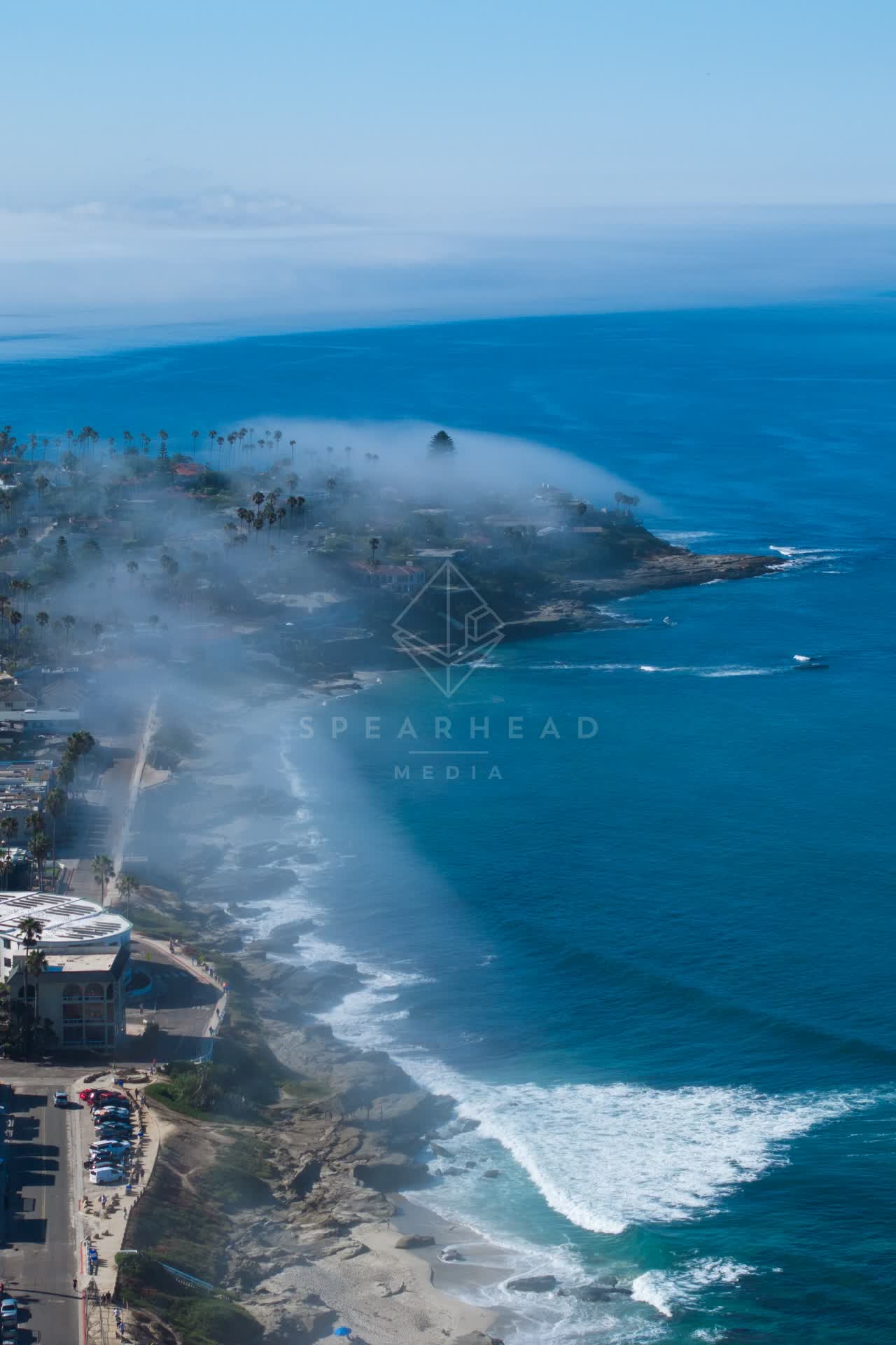 Aerial view of the cliffs, the surf and boats at Windansea, with boats out.