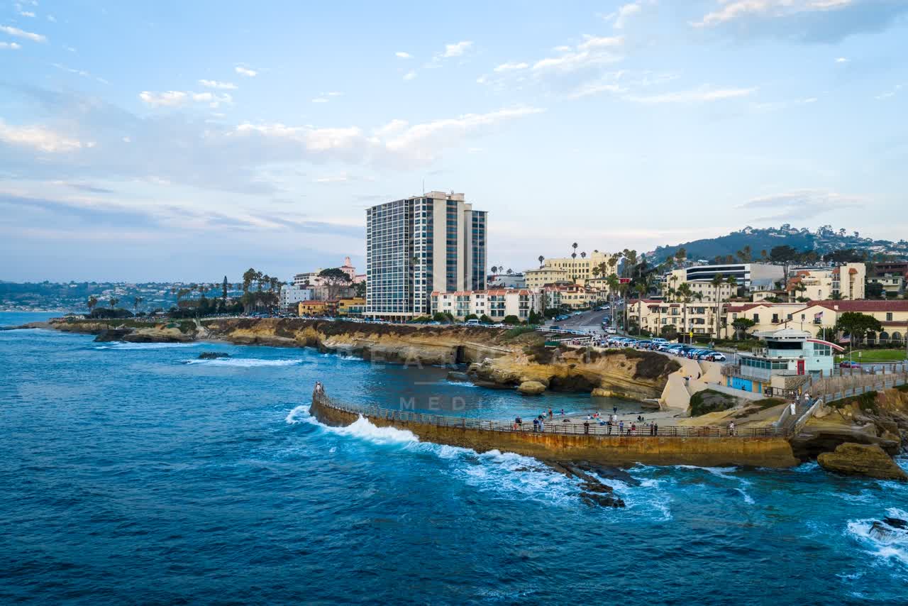 Aerial view of the cliffs, palm trees and the ocean at Village of La Jolla, with people walking.