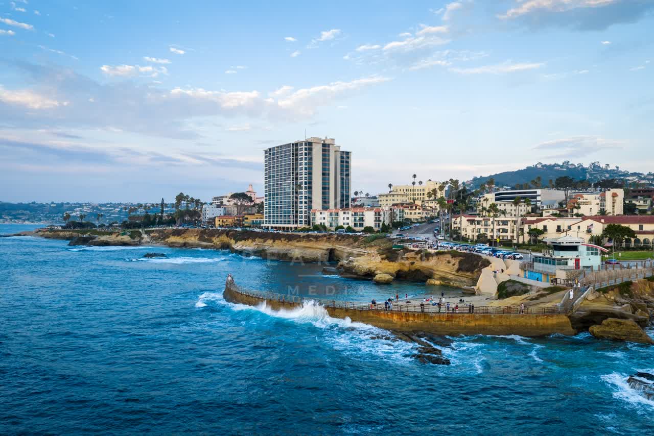 Aerial view of the cliffs, boats and the ocean at Village of La Jolla, with people walking.