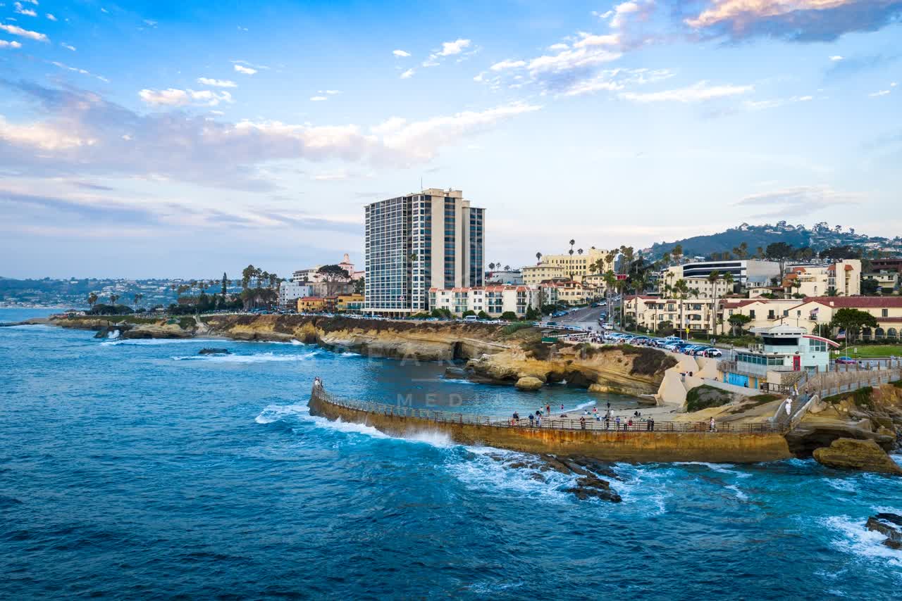 Aerial view of the cliffs, the surf and palm trees at Village of La Jolla, with people walking.