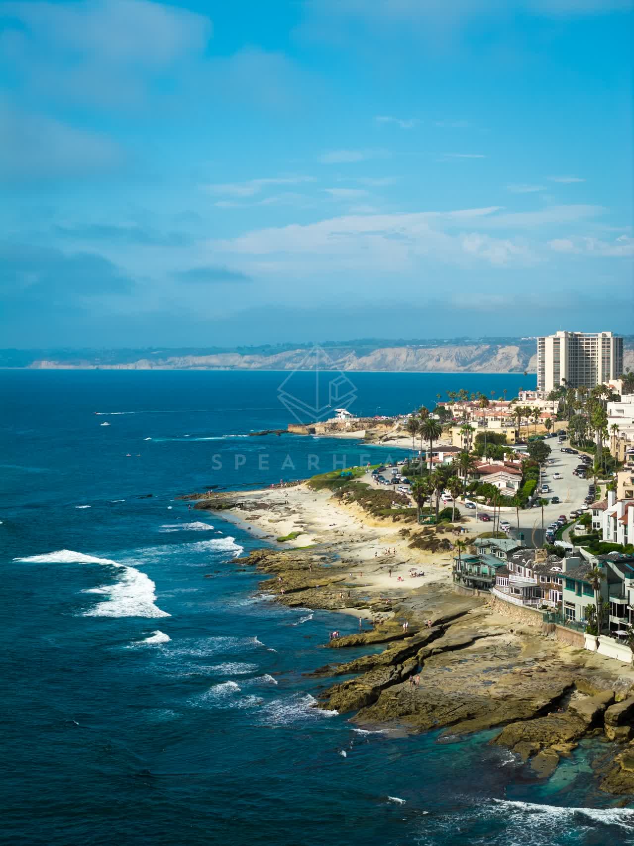 Aerial view of the beach, the surf and palm trees at La Jolla Cove.
