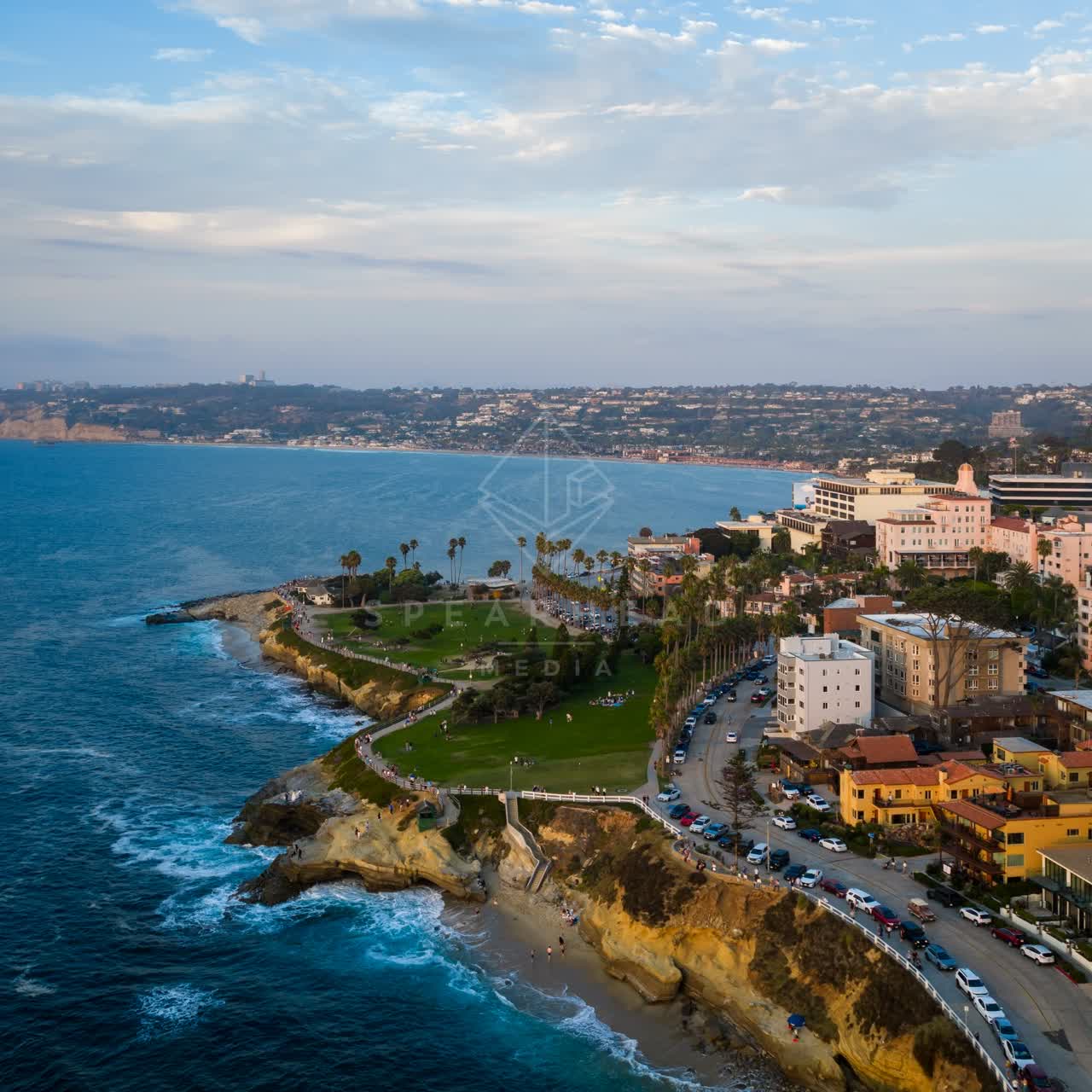 Aerial view of the cliffs, palm trees and the ocean at Village of La Jolla, with people walking.