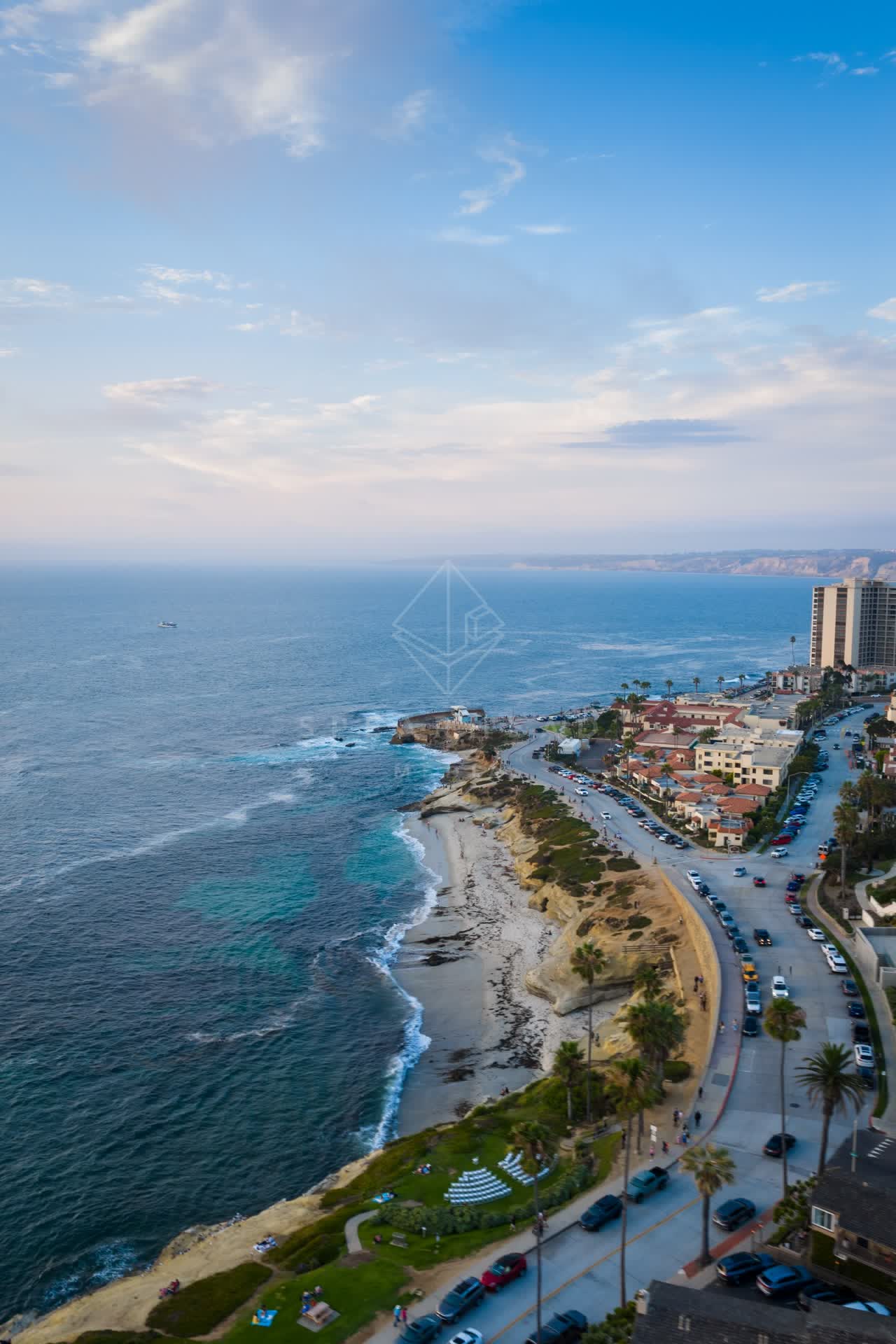 Aerial view of the cliffs, the surf and palm trees at Village of La Jolla, with people walking.