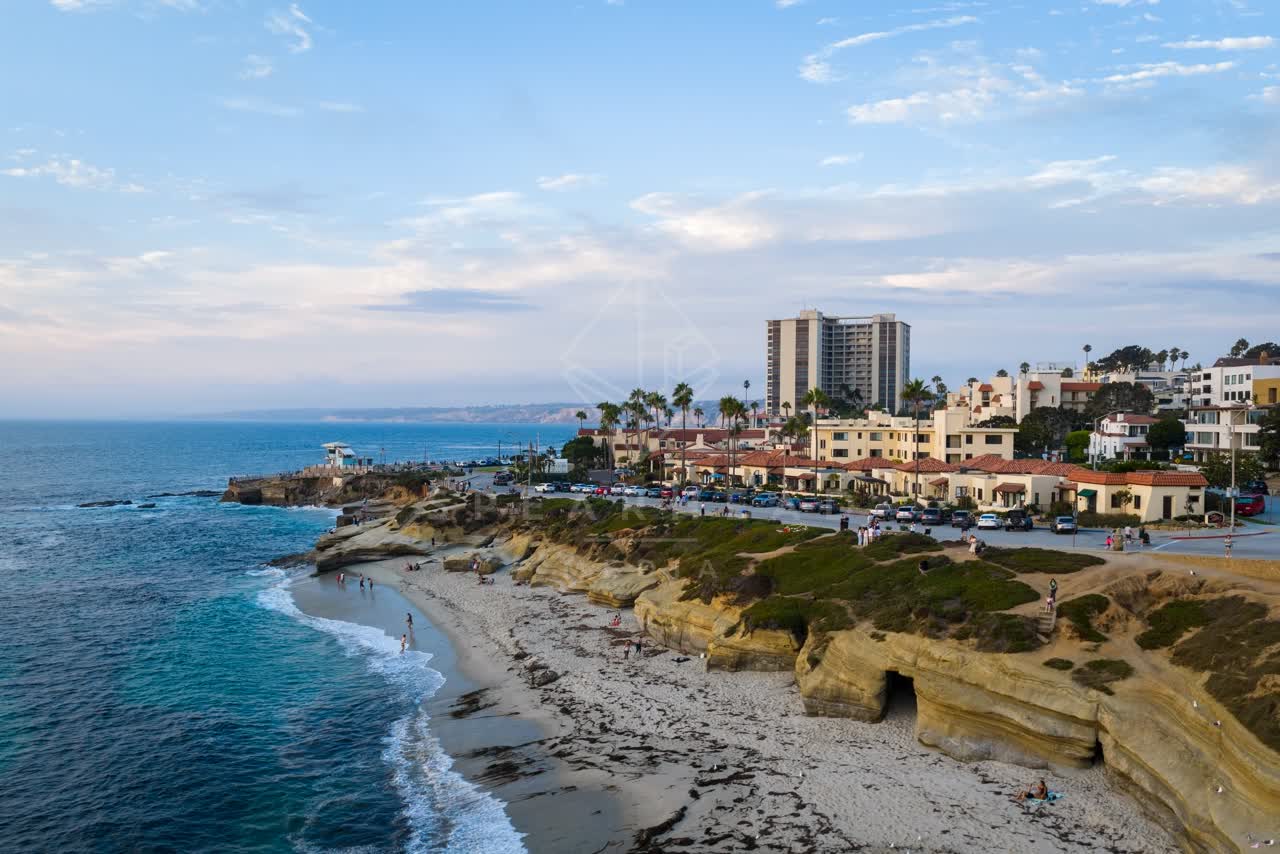 Aerial view of the cliffs, palm trees and the ocean at Village of La Jolla, with people walking.