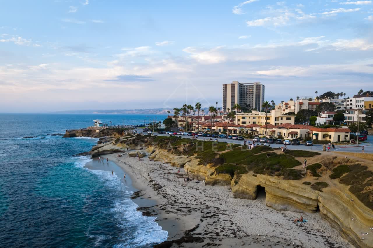 Aerial view of the cliffs, palm trees and the ocean at Village of La Jolla, with people walking.