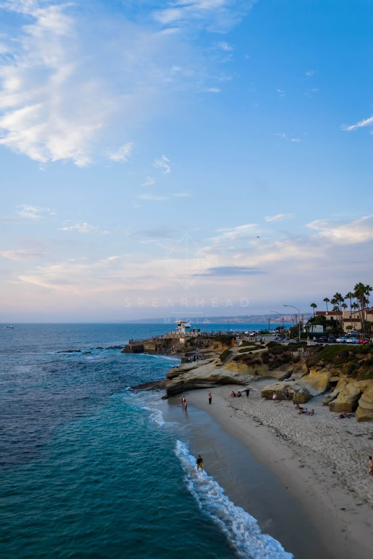 Aerial view of the beach, palm trees and the ocean at Village of La Jolla, with people walking.