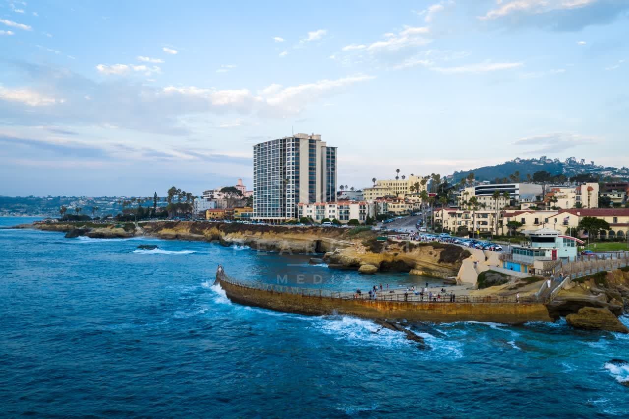 Aerial view of the cliffs, palm trees and the ocean at Village of La Jolla, with people walking.
