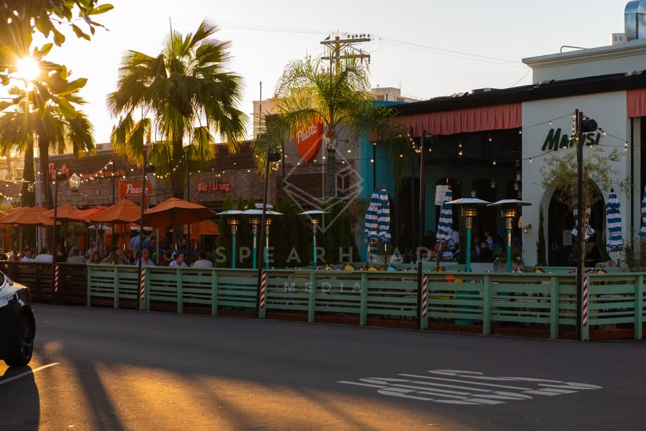 The downtown streets, palm trees and the buildings at Village of La Jolla, with people eating outside.