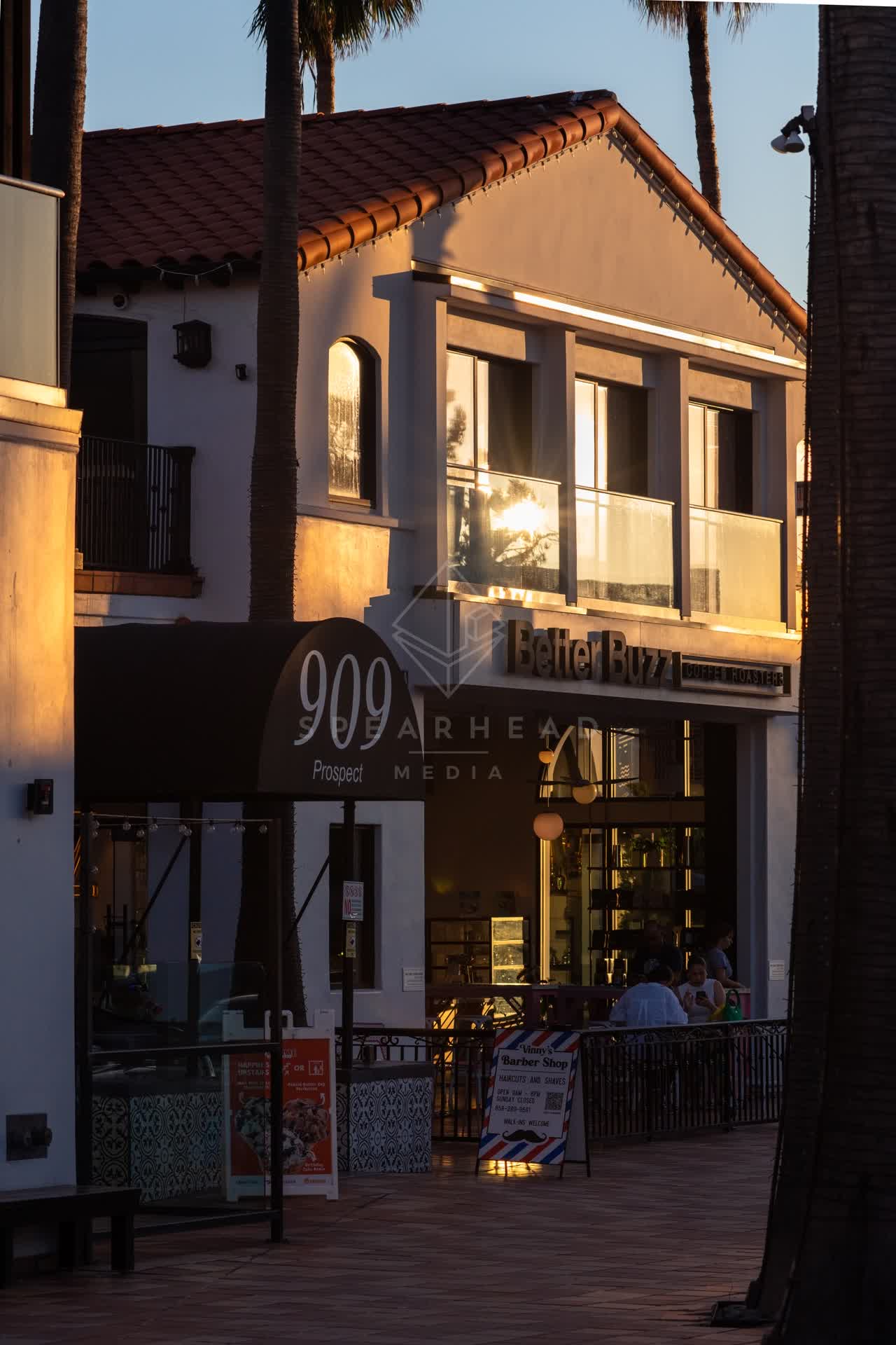 The downtown streets, palm trees and the buildings at Village of La Jolla, with people eating outside.