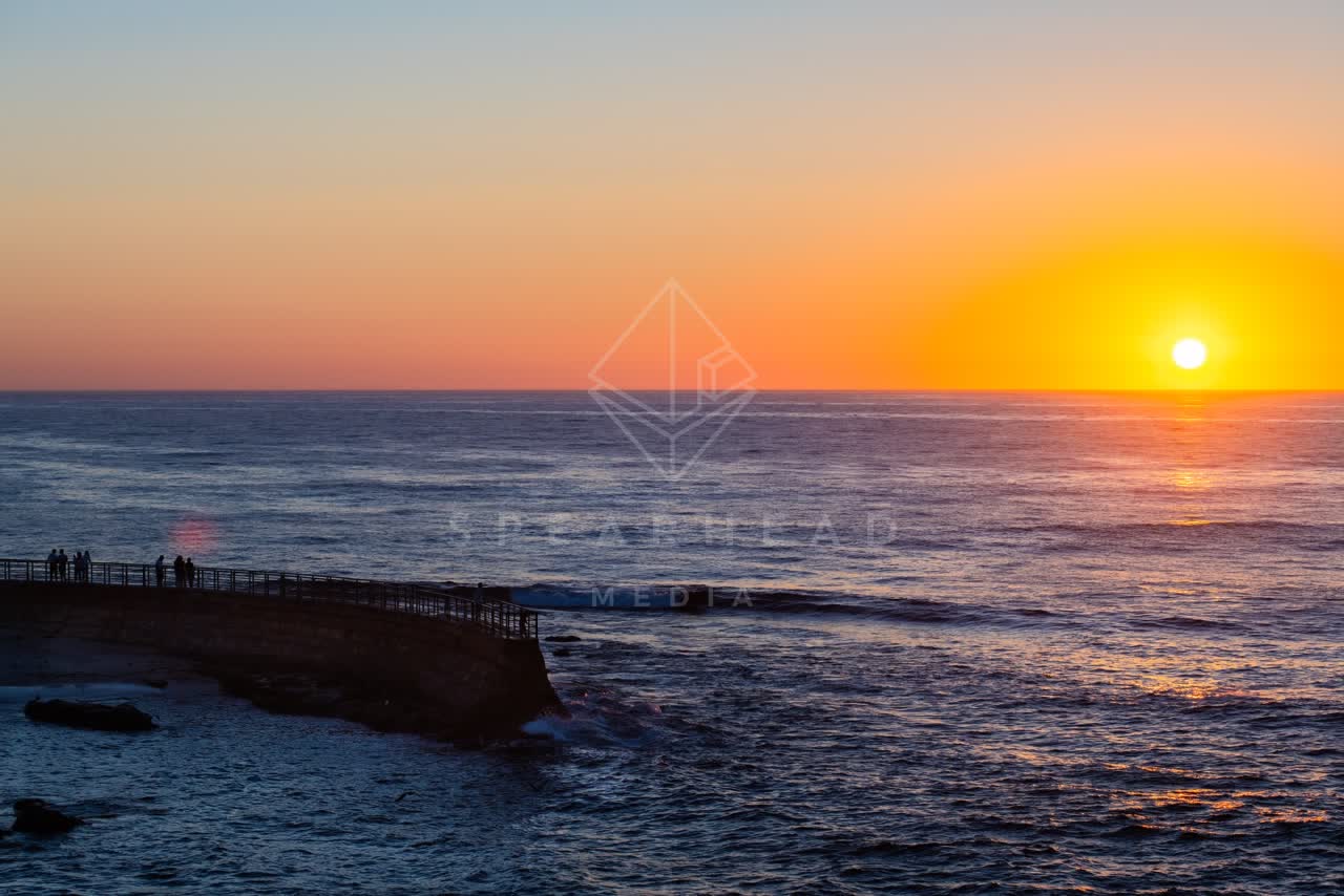 Elevated view of the cliffs, the ocean and open country at La Jolla Cove, with people walking.