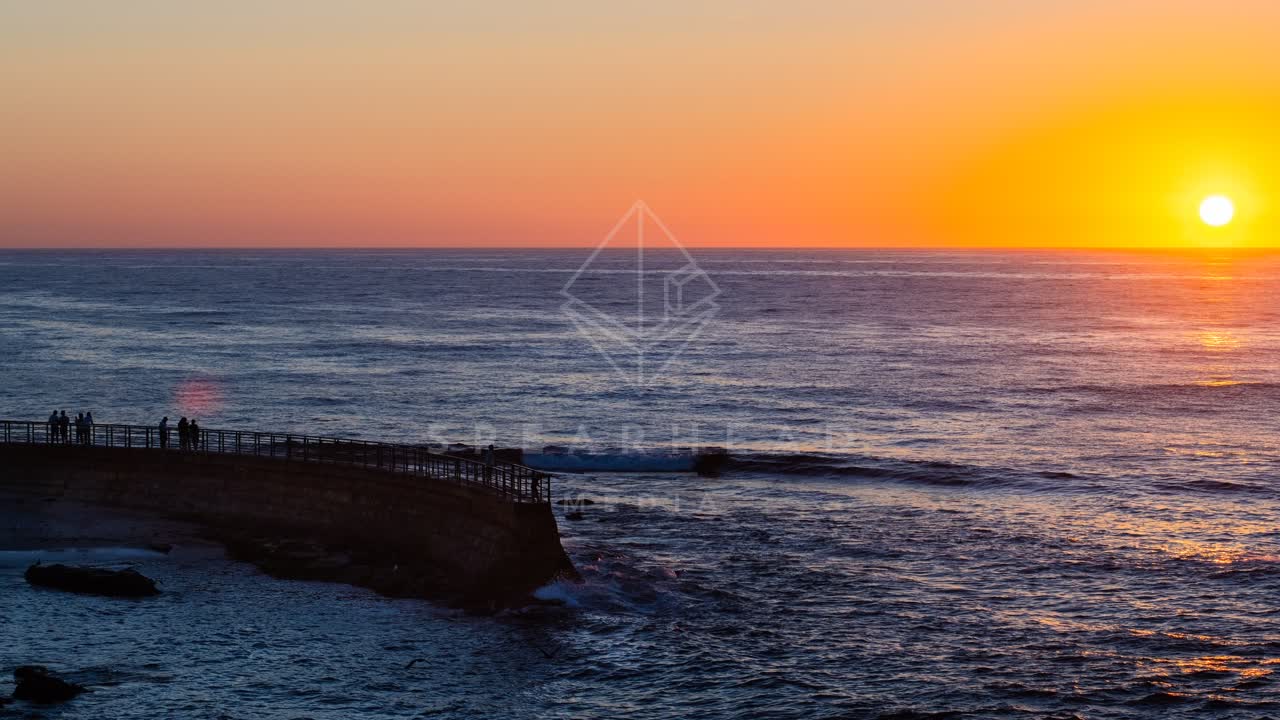 Low aerial view of the cliffs, the ocean and open country at La Jolla Cove, with people walking.