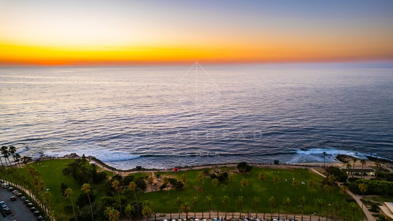 Aerial view of the beach, the surf and palm trees at La Jolla Cove, with people walking.