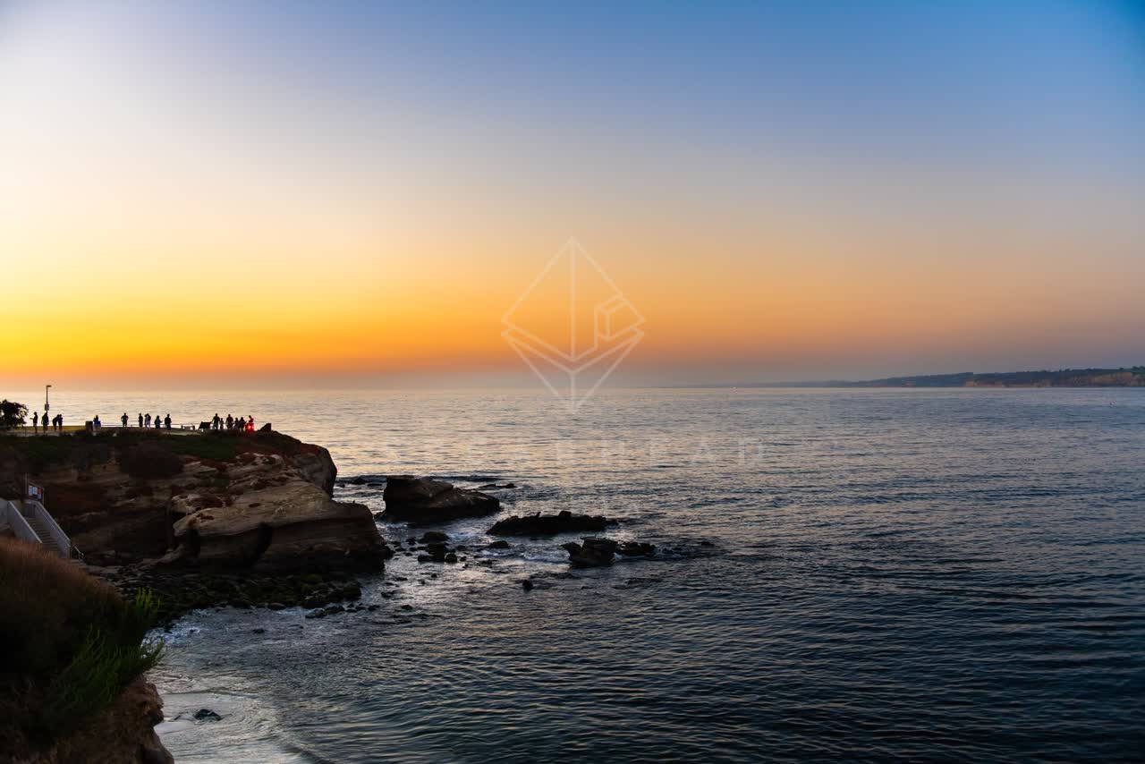 Elevated view of the cliffs, the ocean and open country at La Jolla Cove, with people walking.