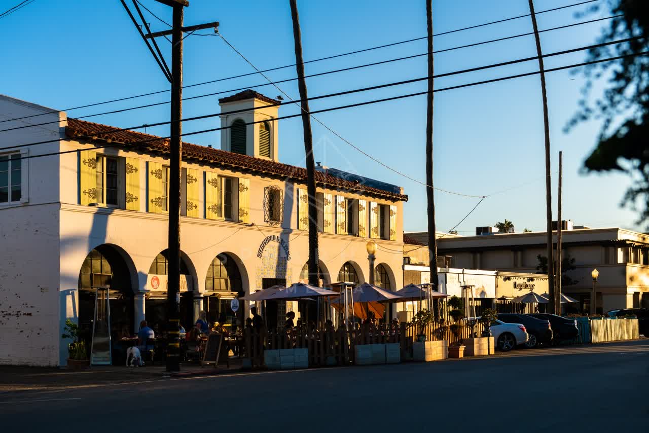 The downtown streets, palm trees and the buildings at Village of La Jolla, with people eating outside.