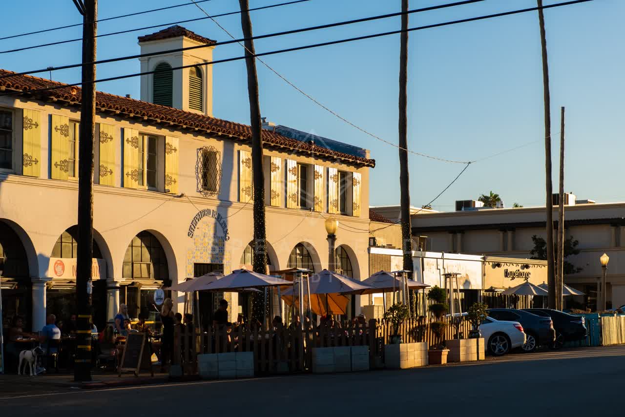 The downtown streets, wildlife and palm trees at Village of La Jolla, with people eating outside.