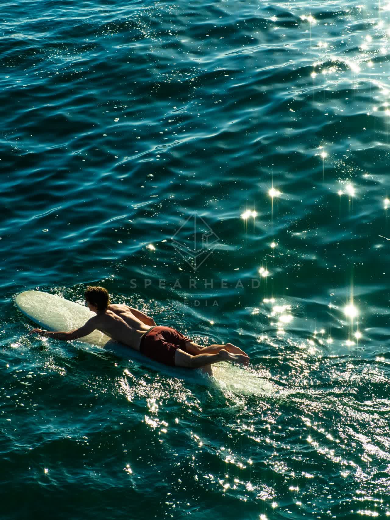 Low aerial view of the beach, the surf and the ocean in Ocean Beach, with paddlers on the water.